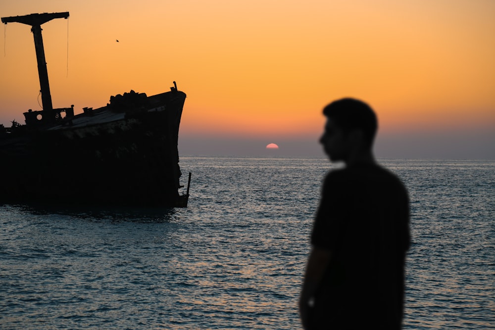 a man standing in front of a boat in the ocean