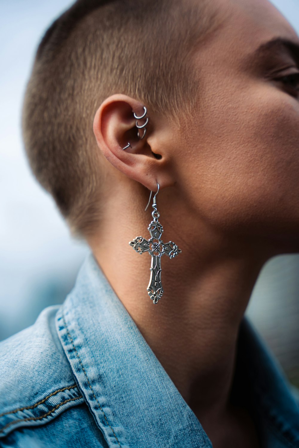 a close up of a person wearing a cross earring