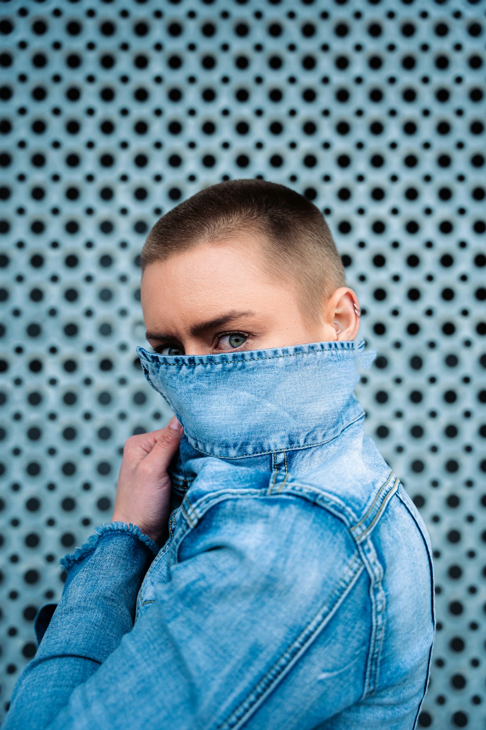 a woman with a denim jacket covering her face