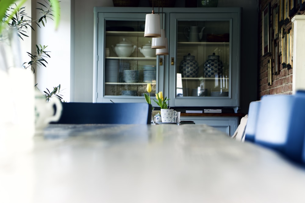 a dining room table with blue chairs and a china cabinet