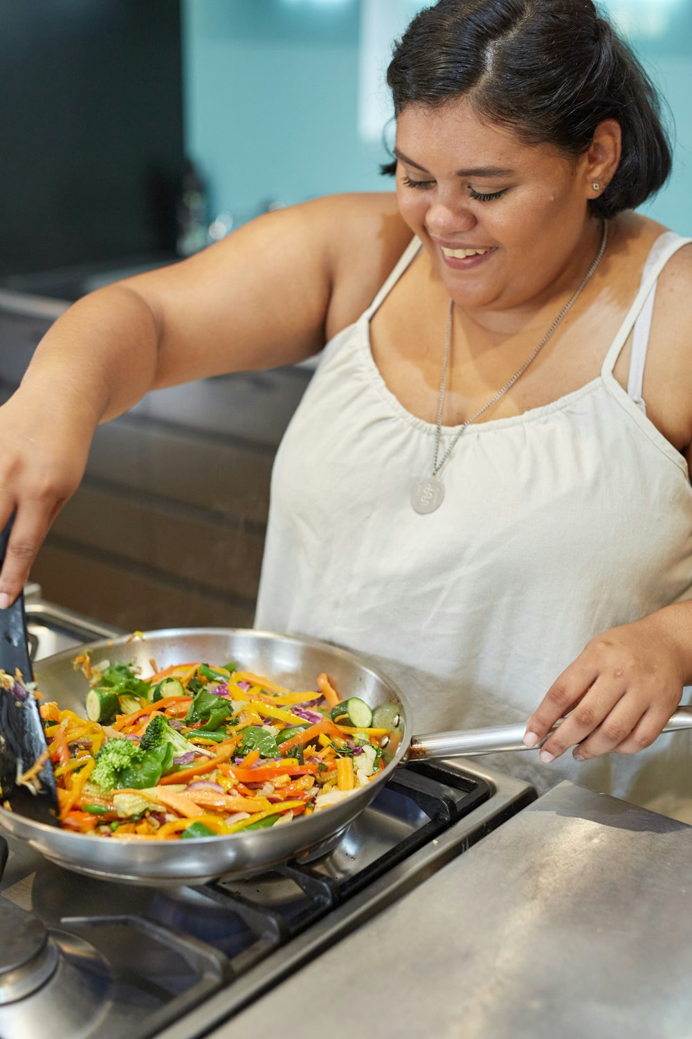 a woman in a white tank top preparing food on a stove