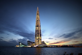 Photo of a sleek, navy-lit skyscraper against a twilight sky.