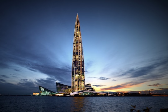 Photo of a sleek, navy-lit skyscraper against a twilight sky.