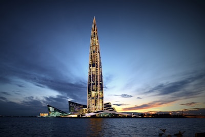 A sleek, modern skyscraper glowing softly against a twilight sky, showcasing elegant architectural lines.