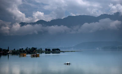 A serene houseboat floating gently on the tranquil Dal Lake surrounded by snow-capped Kashmir mountains.