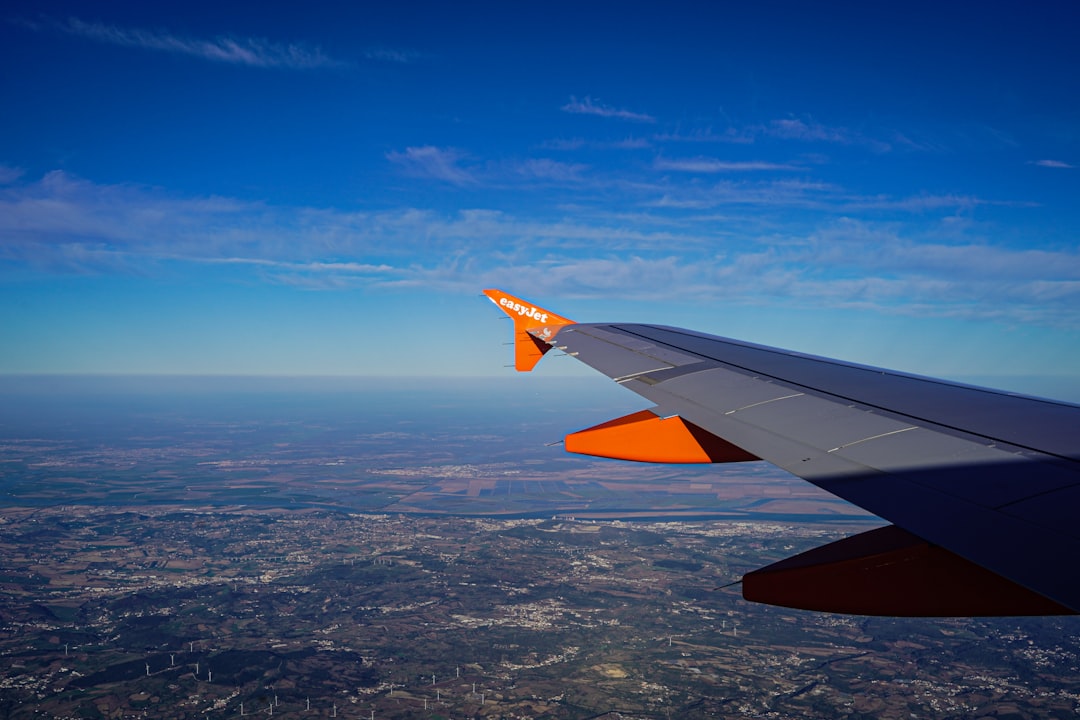 the wing of an airplane flying over a city, Photograph by Mark Stuckey.