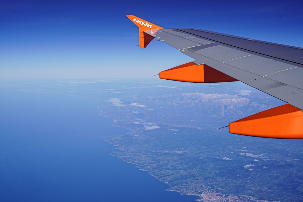 a view of the wing of an airplane flying over a body of water