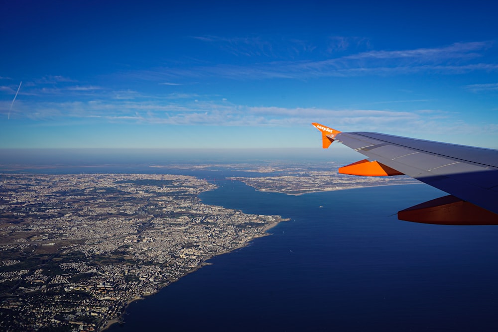 an airplane wing flying over a large body of water