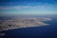 Aerial view of a coastal town with beaches and urban areas under clear blue skies.