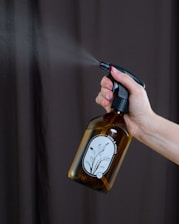 a person spraying a brown bottle with a sprayer