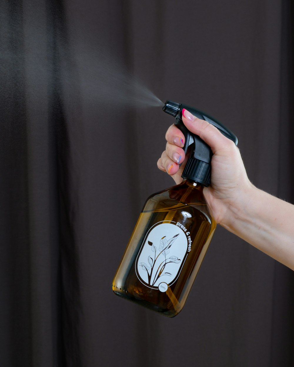 a person spraying a brown bottle with a sprayer