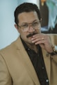 a man with a moustache wearing a suit and glasses