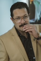 a man with a moustache wearing a suit and glasses
