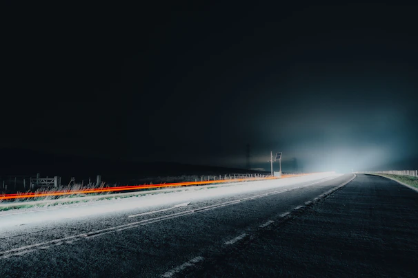 Bright headlights illuminating a dark road at night.
