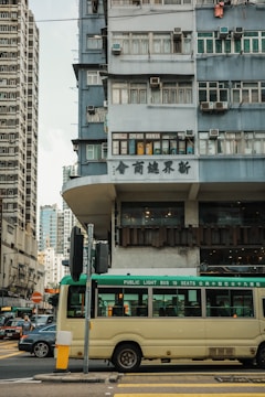 An electric bus navigating through a bustling Hong Kong street lined with greenery.