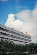 A government building with flags fluttering under a clear blue sky.