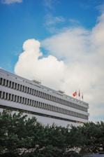 A government building with flags fluttering under a clear blue sky.