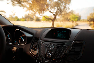 Close-up of a sleek dash cam mounted on a car windshield capturing a sunny road.