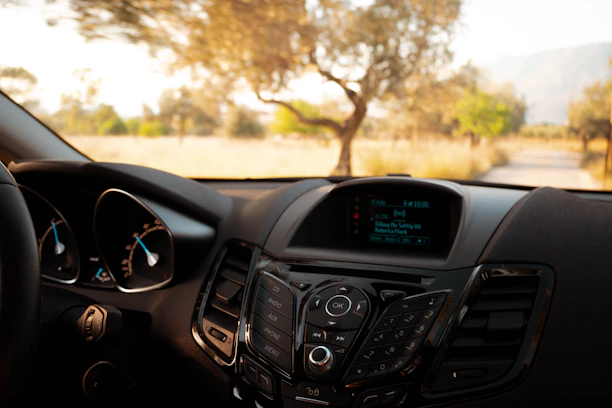 Close-up of a sleek dash cam mounted on a car windshield capturing a sunny road.
