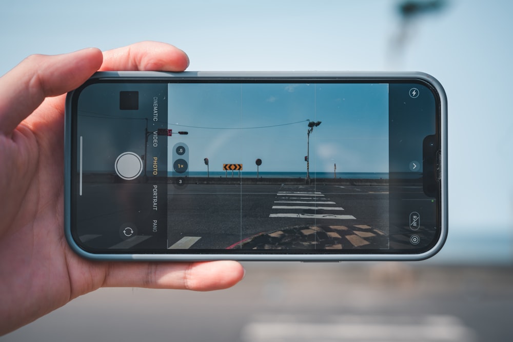 uma pessoa tirando uma foto de uma rua com um telefone celular