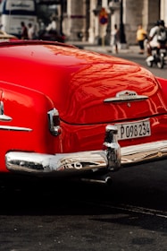 A vibrant red classic car with flawless paint correction reflecting the surrounding cityscape.