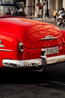 A vibrant red classic car with flawless paint correction reflecting the surrounding cityscape.