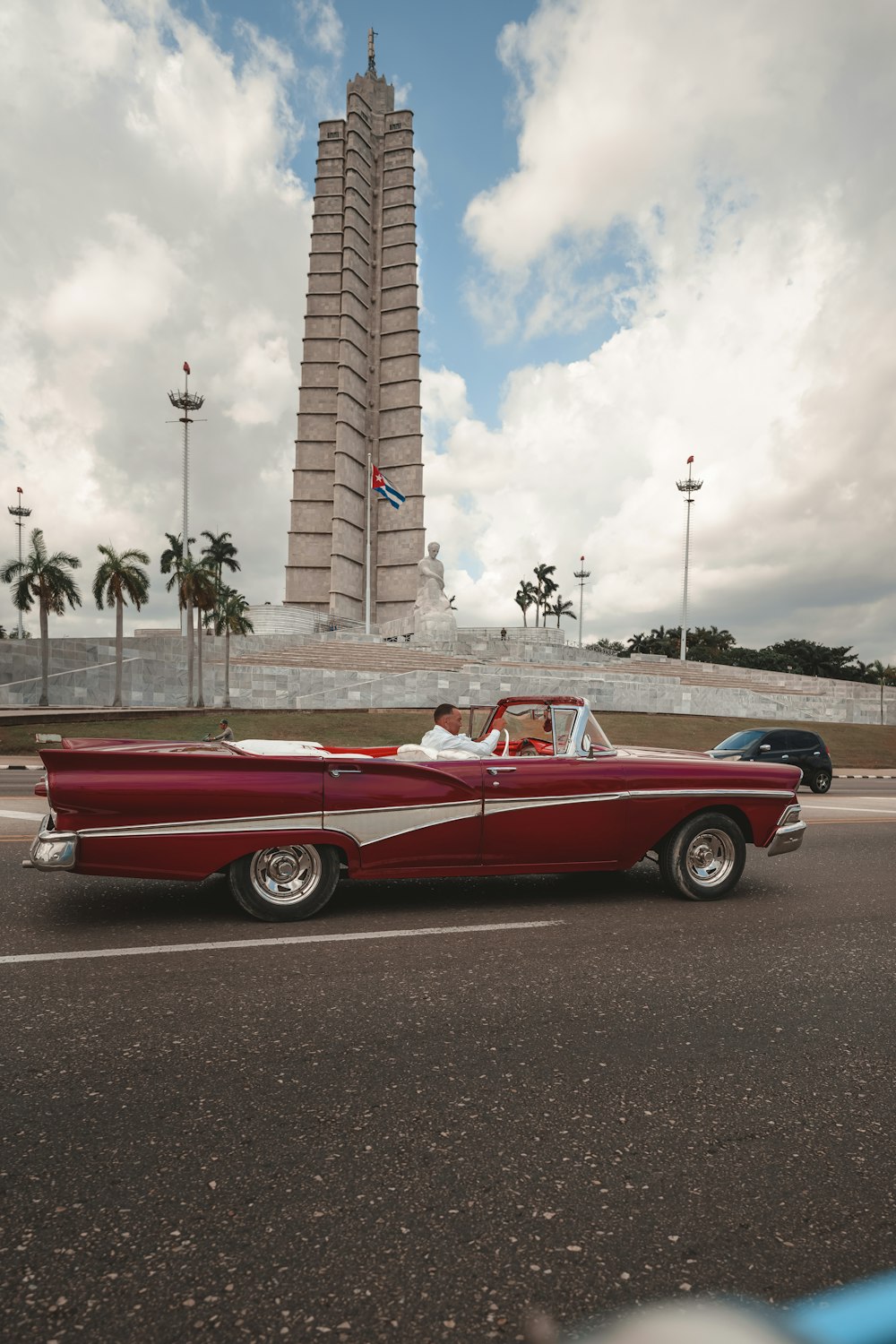 a red car driving down a street next to a tall building