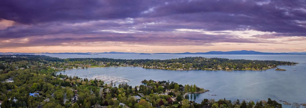 a lake surrounded by trees under a cloudy sky