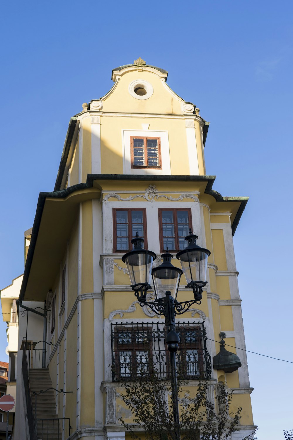 a tall yellow building with a clock on the top of it