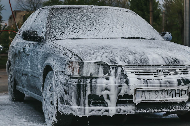 A friendly Aquavelo team member gently washing a car outdoors using eco-friendly products.