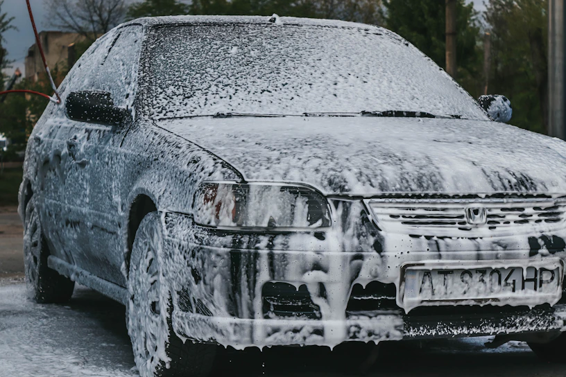 A sleek car being washed with foam and water.