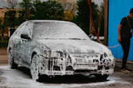 Side view of a house exterior mid-wash, with water spraying and dirt washing away.