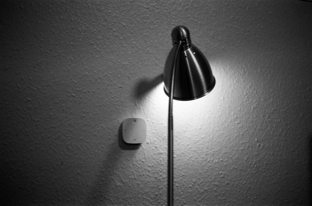 a black and white photo of a lamp on a wall