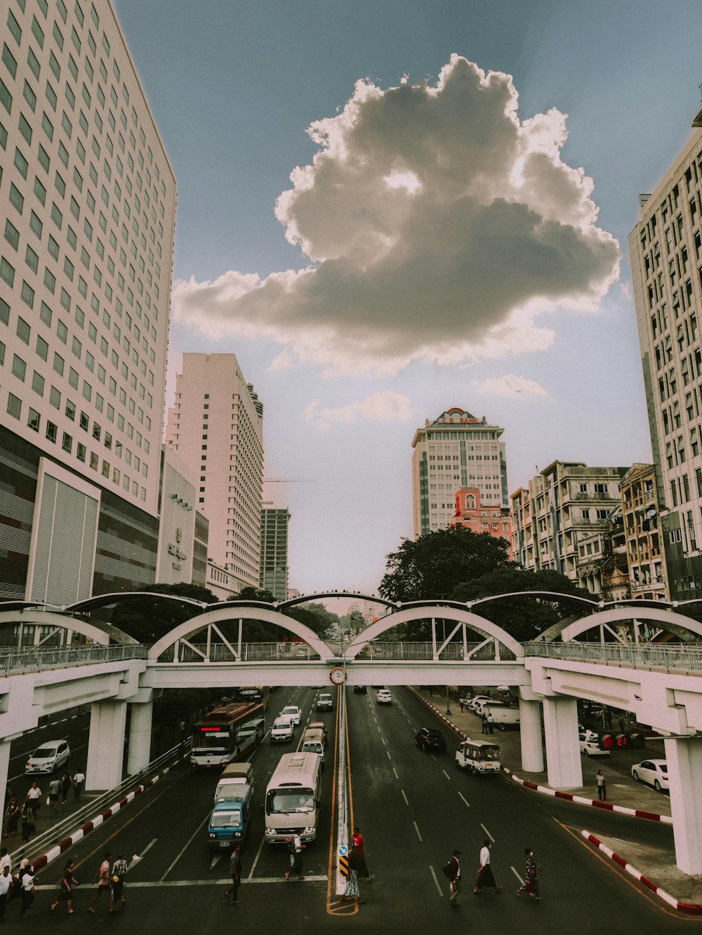 a cloudy sky over a city street with tall buildings