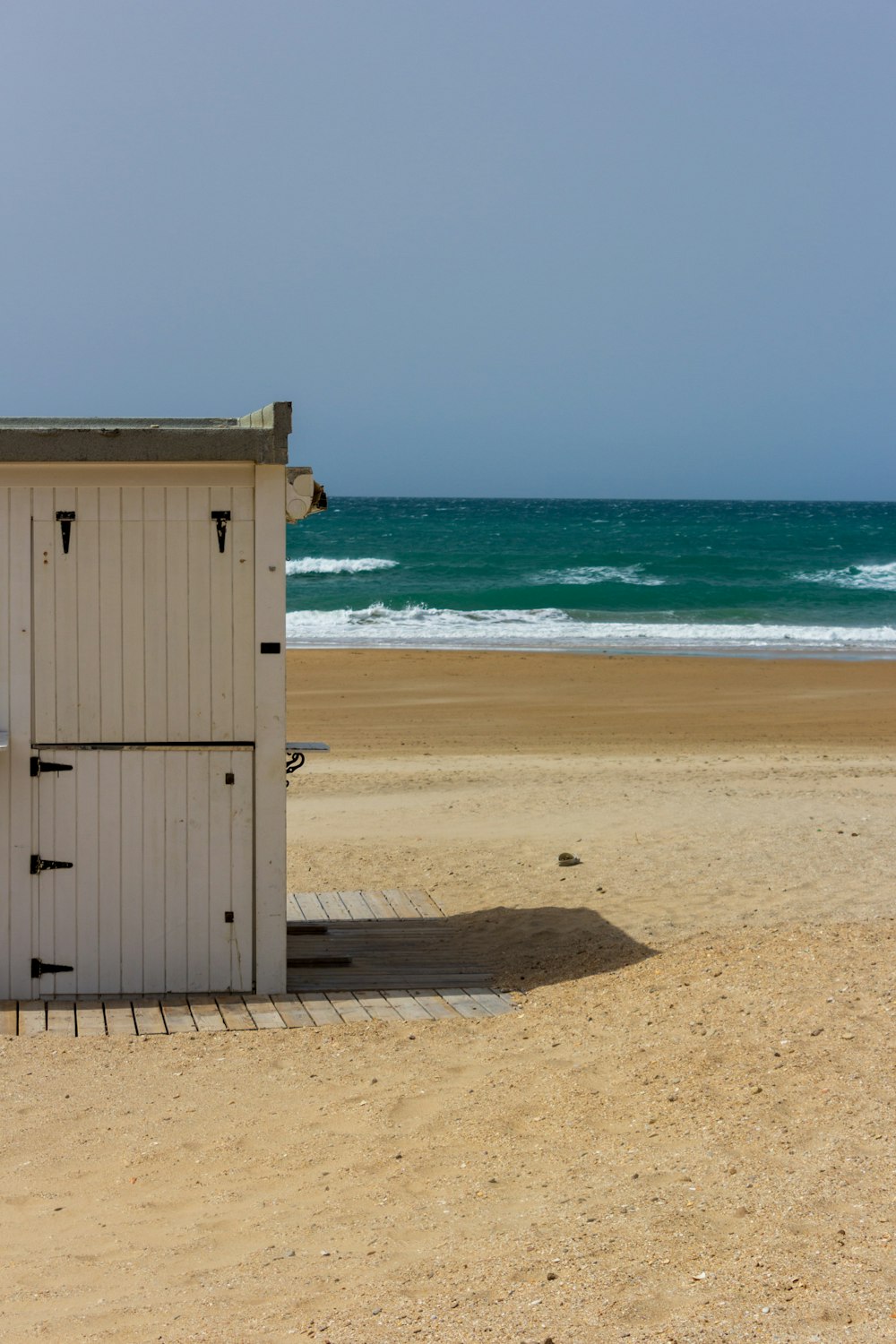 a white outhouse sitting on top of a sandy beach