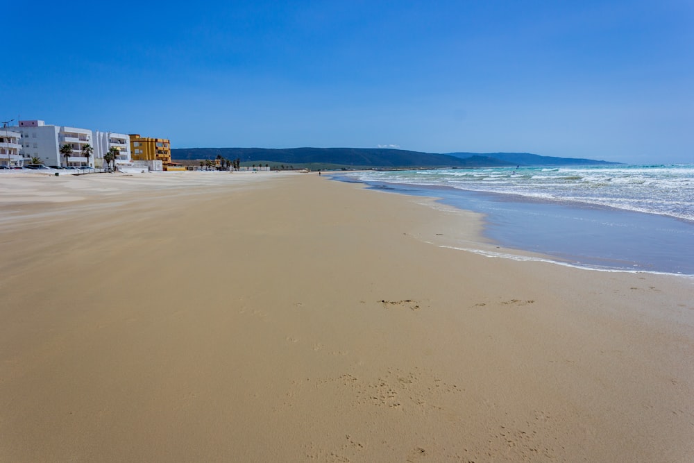 a sandy beach with buildings in the background