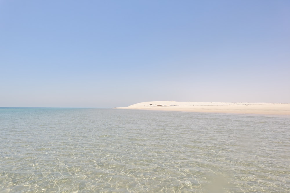 a large body of water sitting under a blue sky