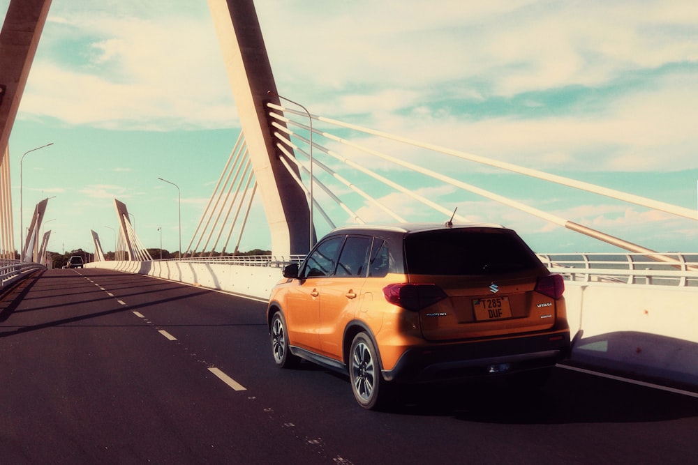 an orange car is driving across a bridge