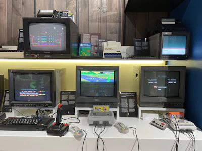 Display of various retro consoles like Atari, Sega, and Intellivision neatly arranged on wooden shelves.