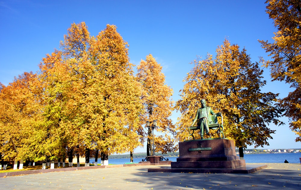 a statue of a man in a park surrounded by trees