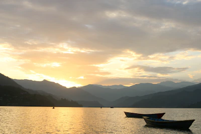 A serene morning scene with a boat gliding across the calm lake waters.