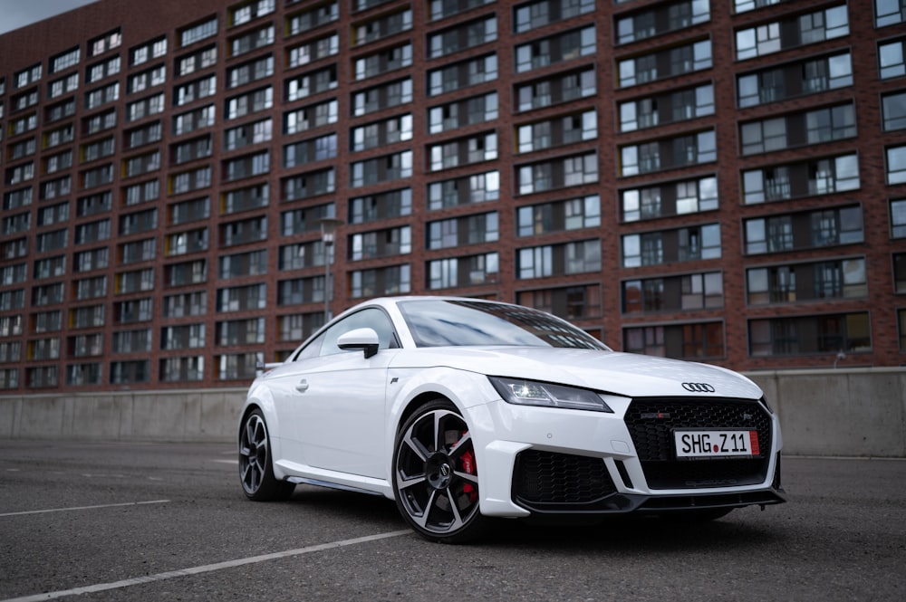 a white car parked in front of a tall building