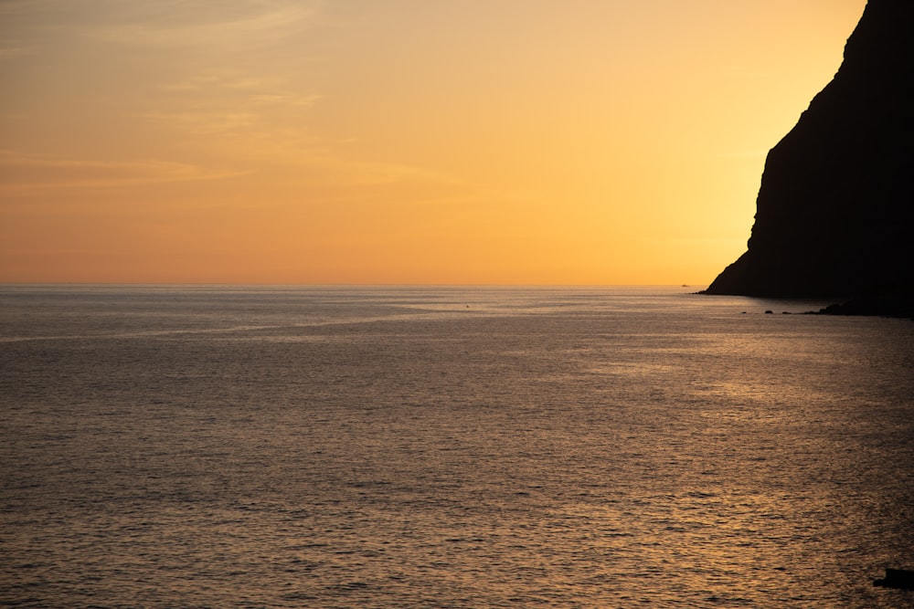 the sun is setting over the ocean with a boat in the water