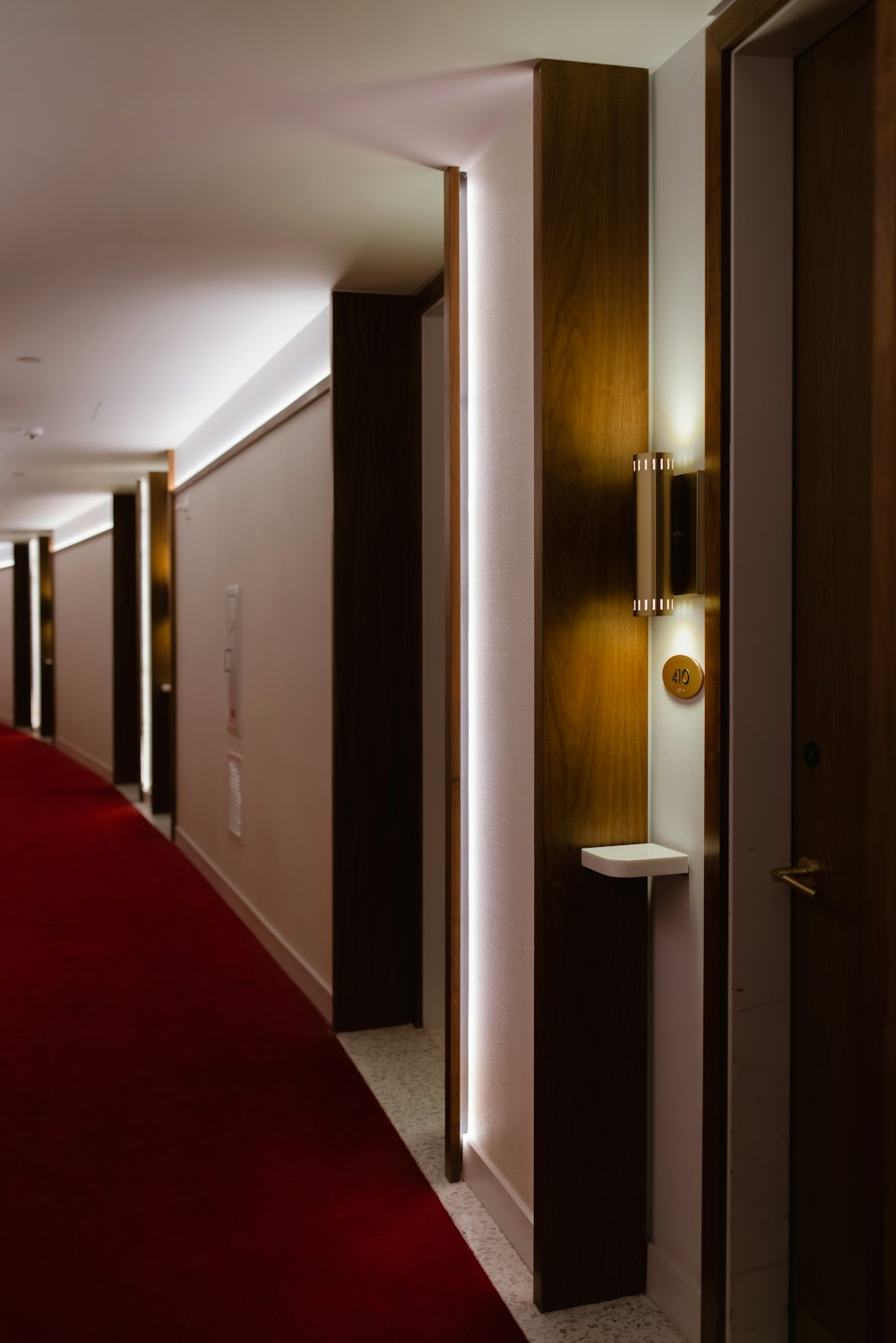 a hallway with a red carpet and a light on the wall