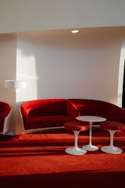 a red couch and two white tables in a room
