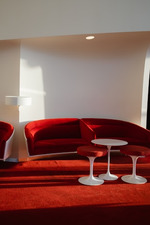 a red couch and two white tables in a room