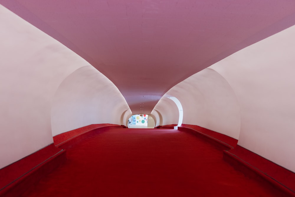 a tunnel with a red carpet and white walls