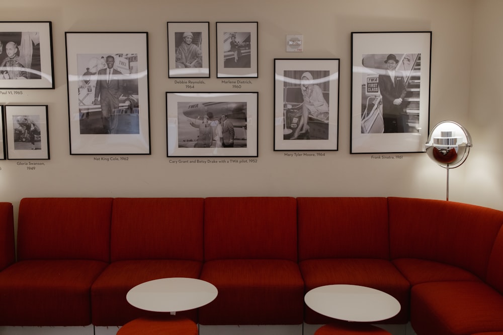 a red couch sitting in front of a wall with pictures on it