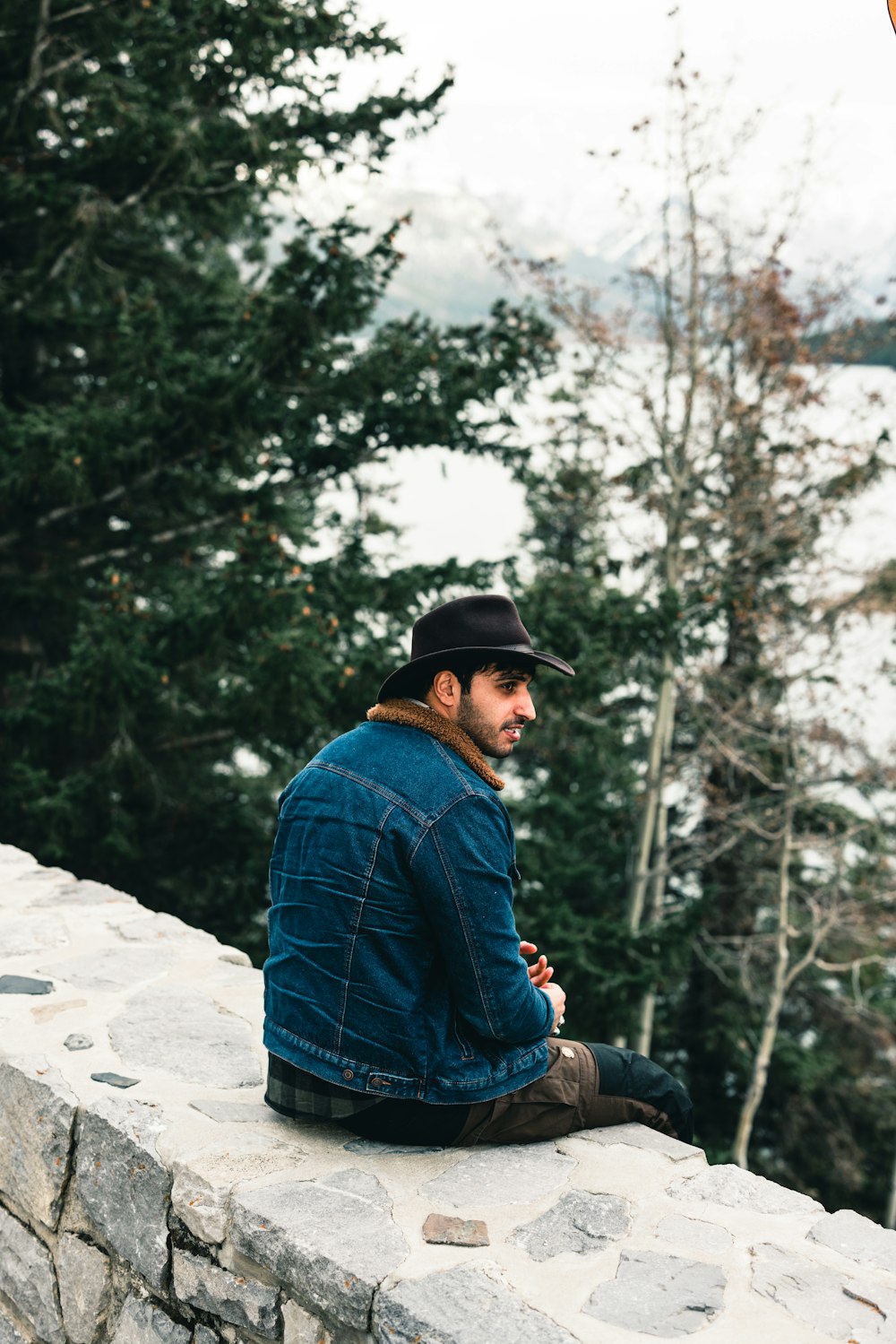 a man sitting on top of a stone wall