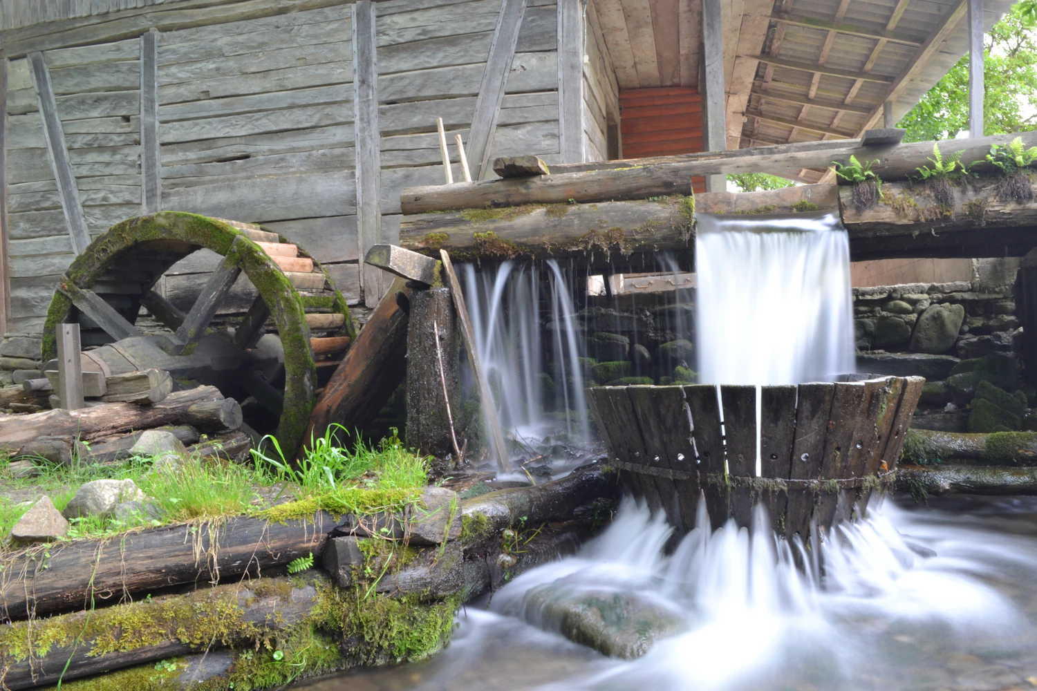 An old timber mill with a wheel beside falling water and mossy stones